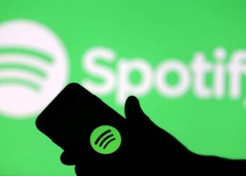 Spotify é alvo ação judicial por suposta omissão de streams falsos que beneficiariam Drake e outros grandes artistas Homem segurando celular com logo do Spotify à mostra