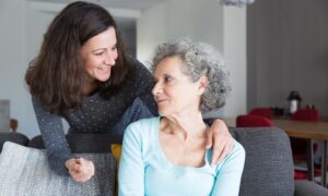 Sorrindo, filha adulta cuida da mãe idosa