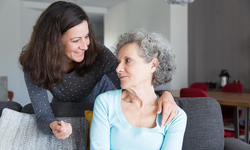 Sorrindo, filha adulta cuida da mãe idosa